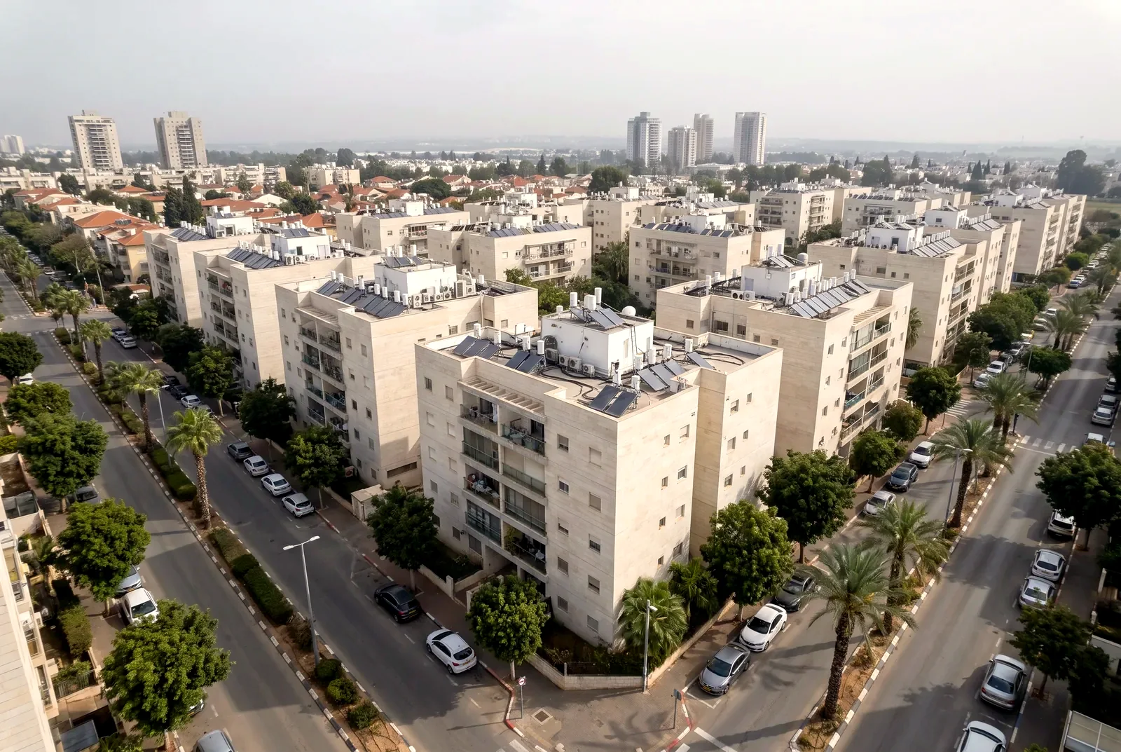 Illustration: an angled aerial view of a residential neighborhood with four- to six-storey apartment buildings, fig trees and palms along the streets, and residential towers on the horizon.