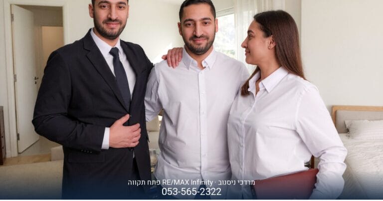 מרדכי ניסנוב, מתווך RE/MAX, מחייך בחליפה ועניבה על רקע משרד בפתח תקווה