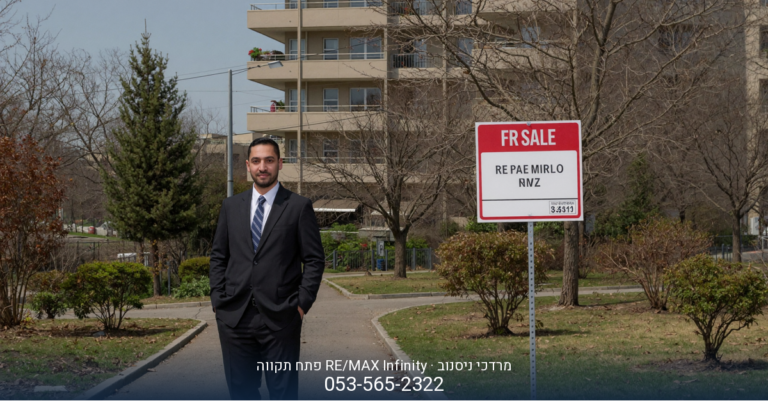 מרדכי ניסנוב, מתווך RE/MAX, עומד בחליפה ליד שלט "למכירה" בפתח תקווה